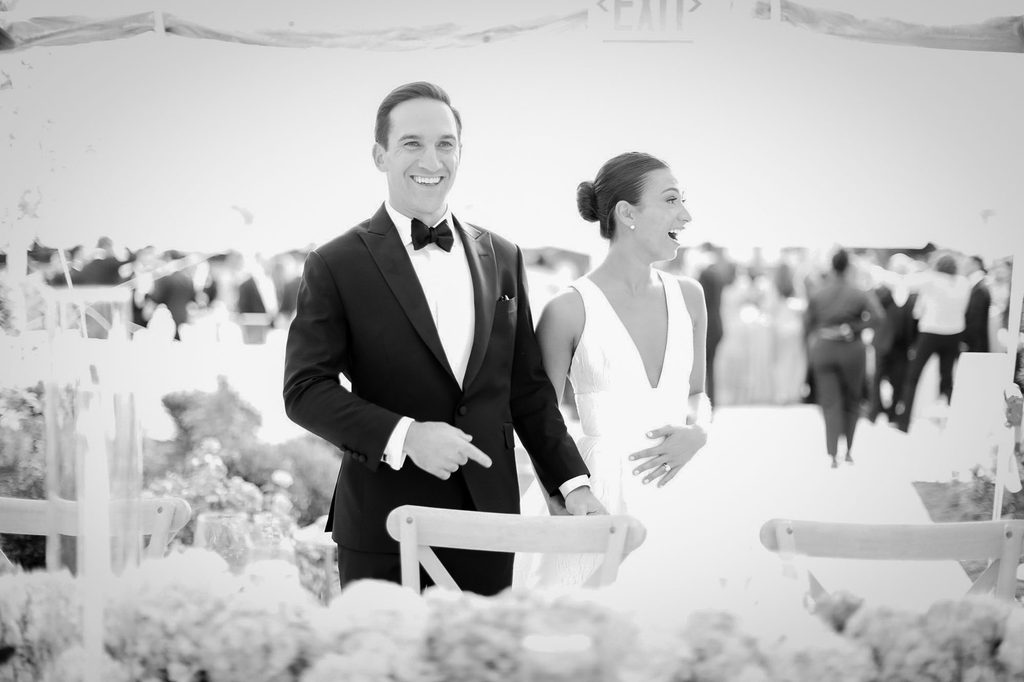 Bride and groom laughing together at an outdoor tented wedding reception, black and white photo