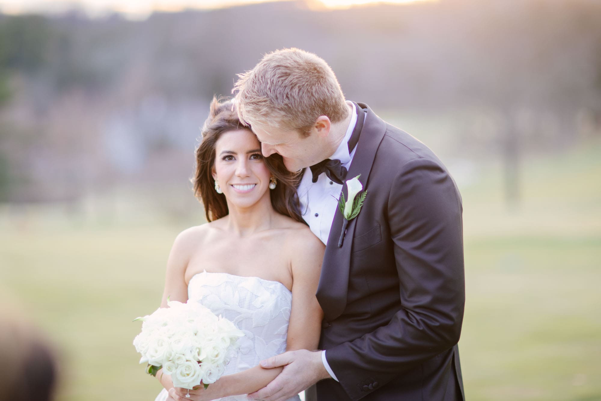 Bride and groom sharing a quiet moment together at golden hour, groom leaning in close to his smiling bride