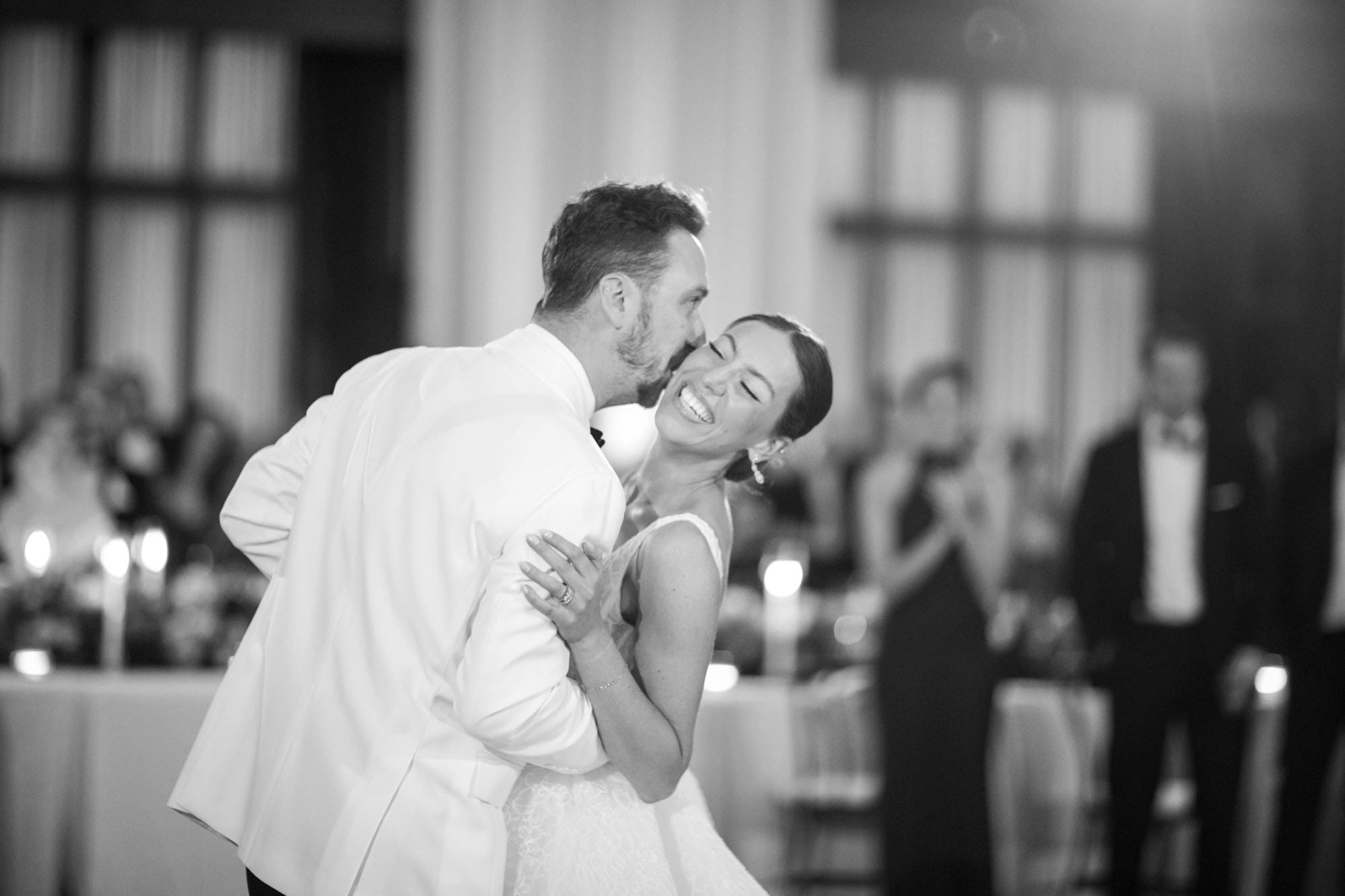 Bride laughing as her groom whispers to her during their first dance
